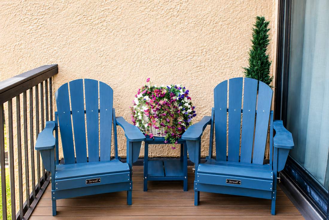Private balcony with blue Adirondack chairs and flowers